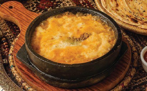 Saltah in een stenen pot met brood ernaast